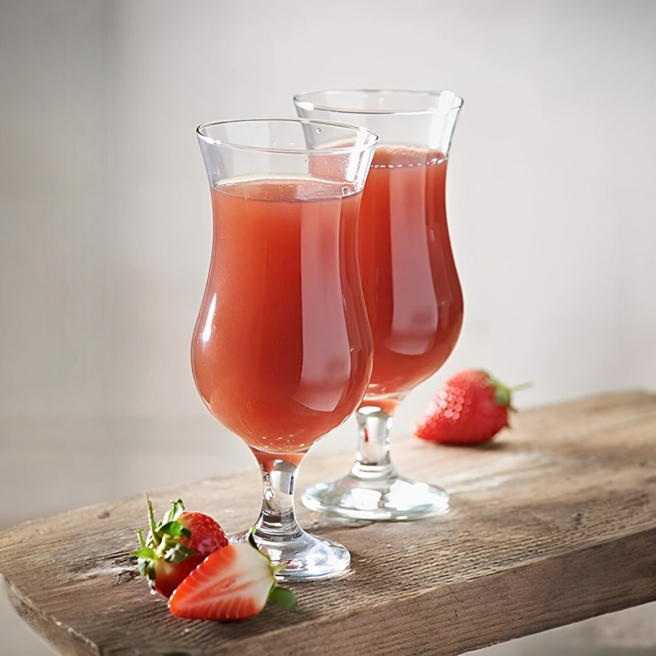 Dos copas huracán 15 1/2 oz con bebida roja y fresas sobre madera