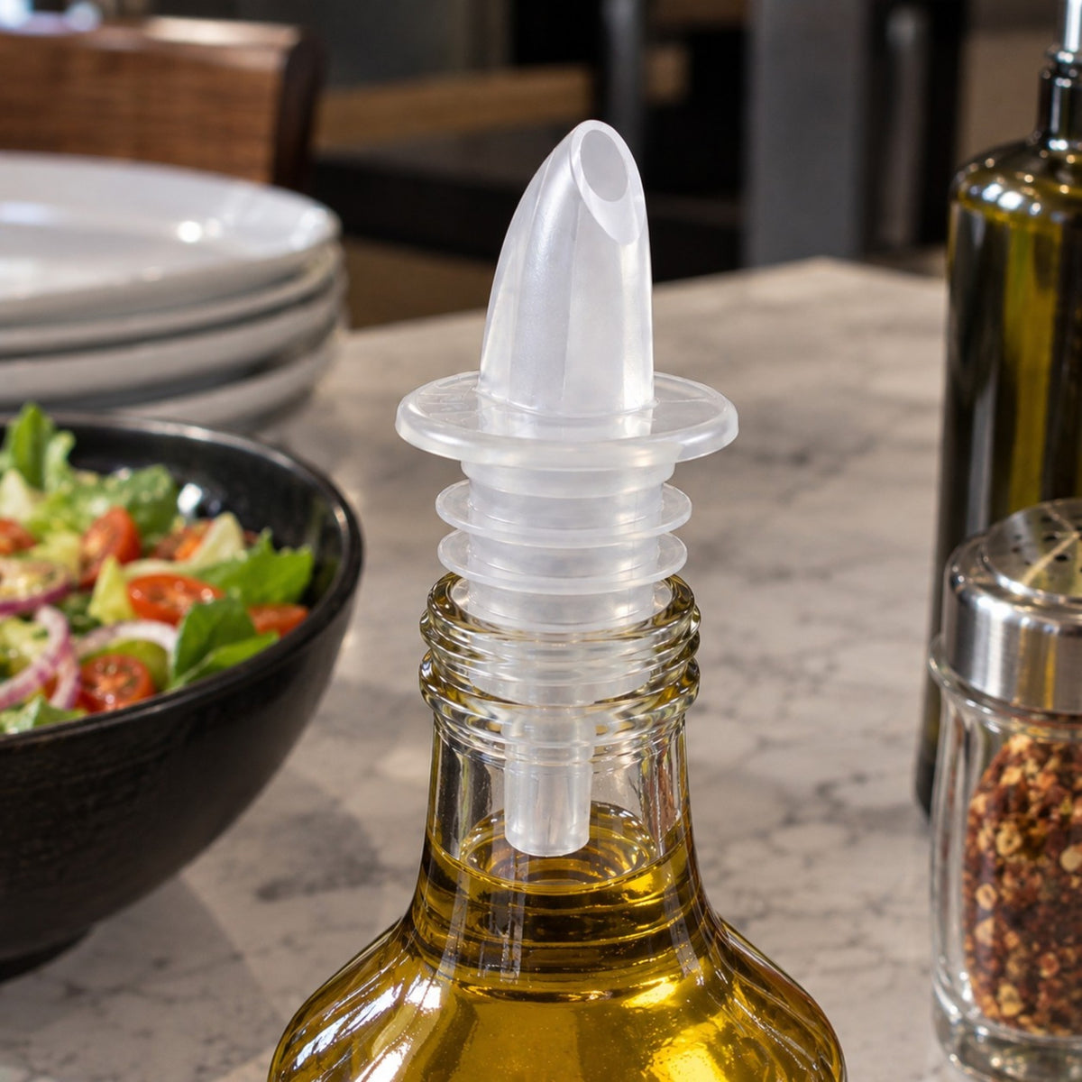 Dosificador de flujo transparente Thunder Group colocado en una botella en una barra de restaurante.